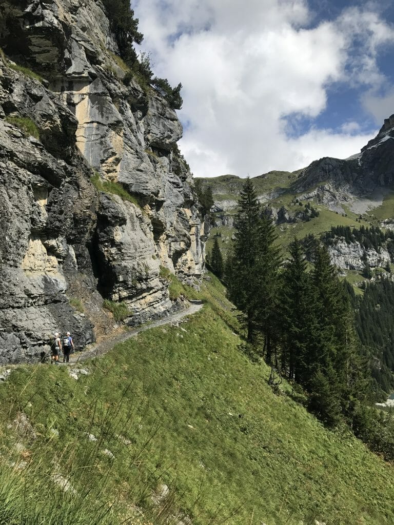 picture of oeschinensee hiking - mountains and greenery in the foreground, with a blue sky in the background.